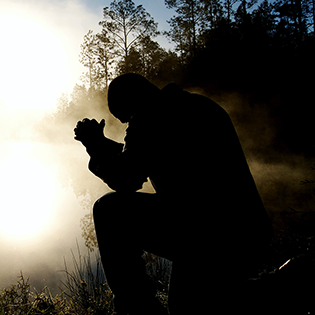Man praying by misty pond