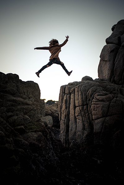 Girl jumping over rocks